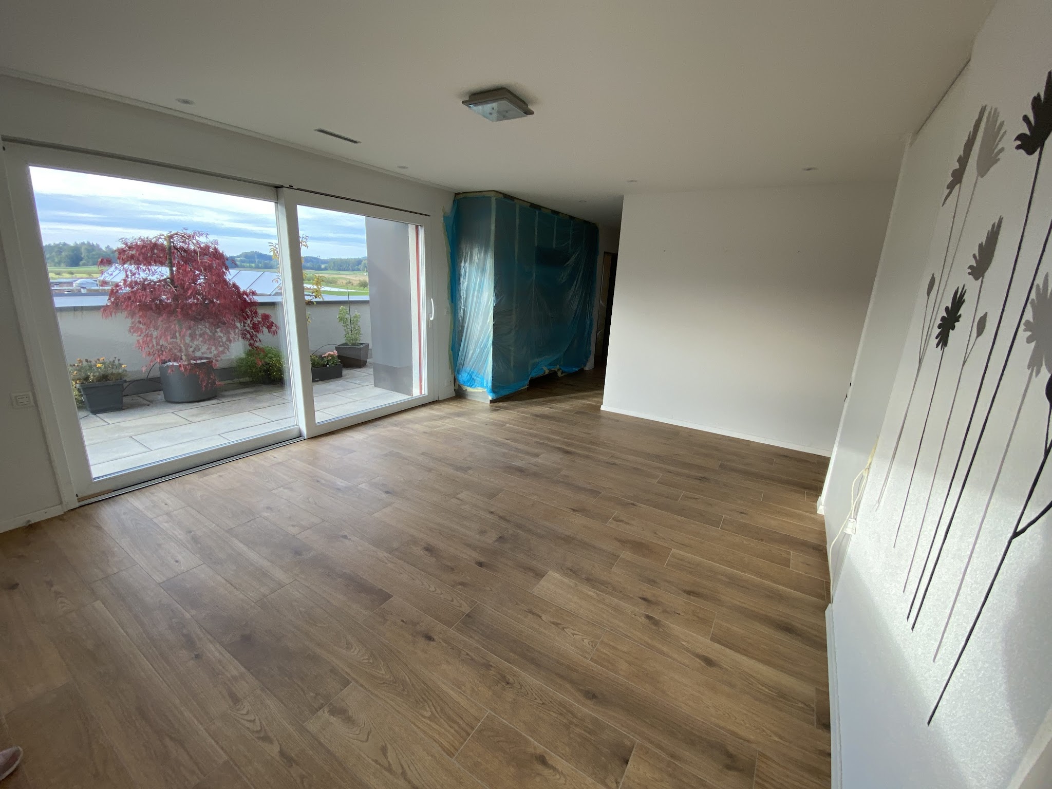 Wohnraum mit Boden in Holzoptik und Blick auf die Terrasse