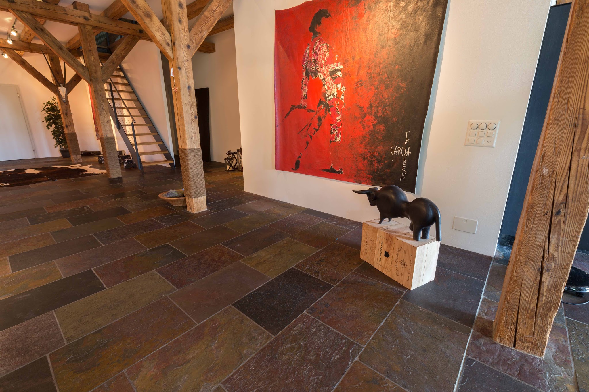 Loft mit mehrfarbigem Schieferboden zwischen alten Holzbalken