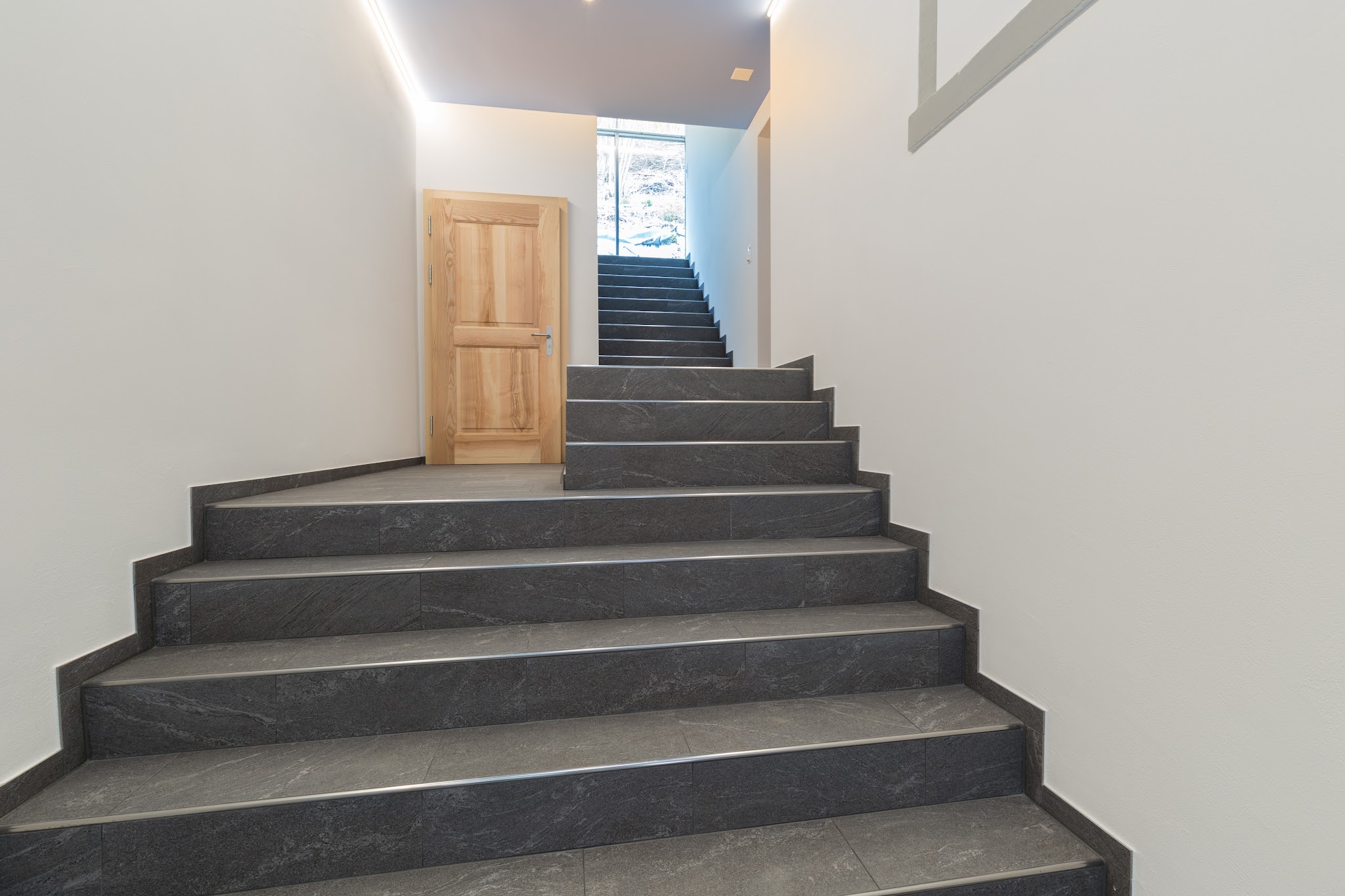 Treppe mit Tritten und Setzstufen aus dunklen Platten