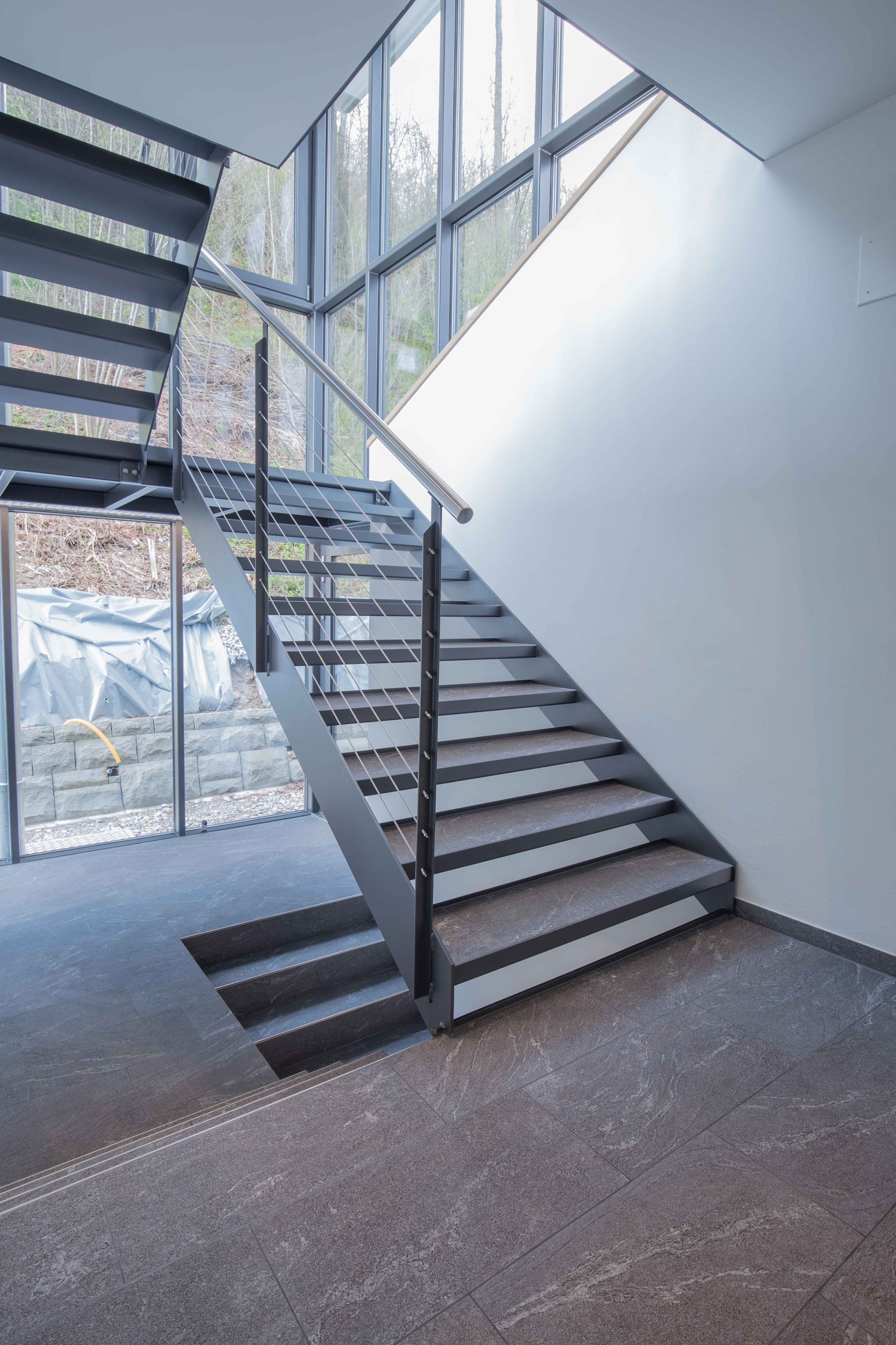 Treppenhaus mit Glasfront und dunklem Plattenboden