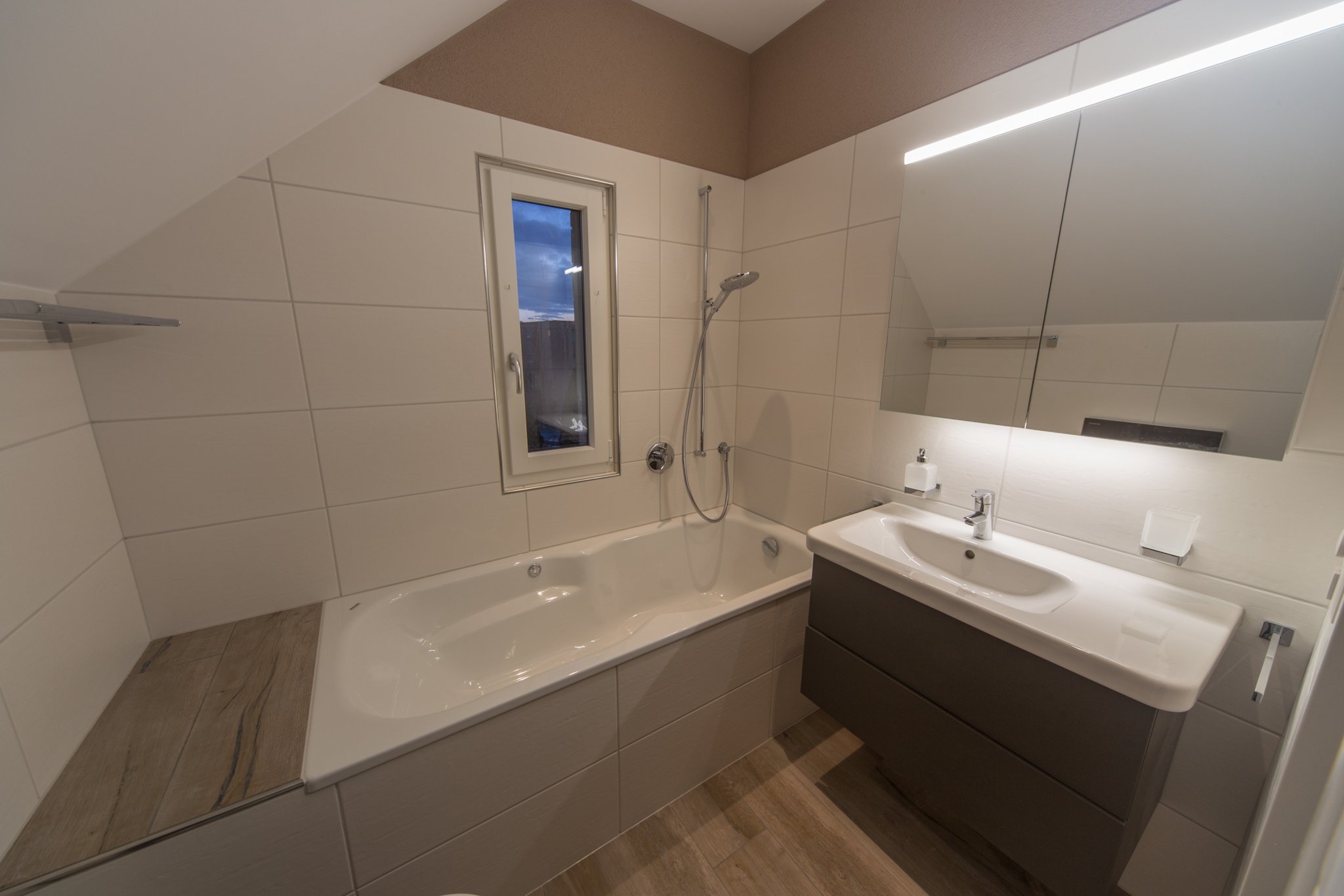 Bad mit Badewanne, grauen Platten und Waschtischmöbel