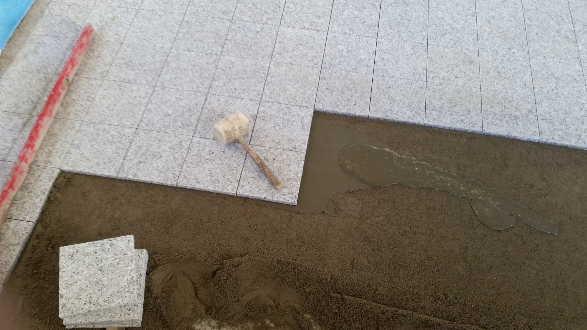 Granitplatten werden ins Mörtelbett gelegt
