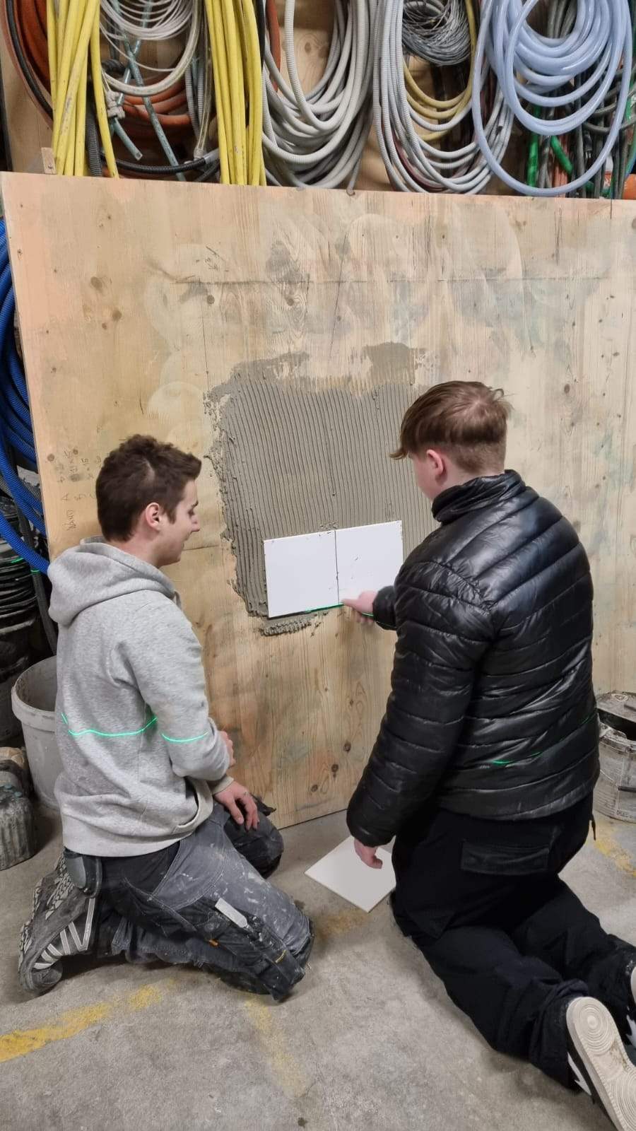 Zwei Schüler setzen Platten an eine Übungswand
