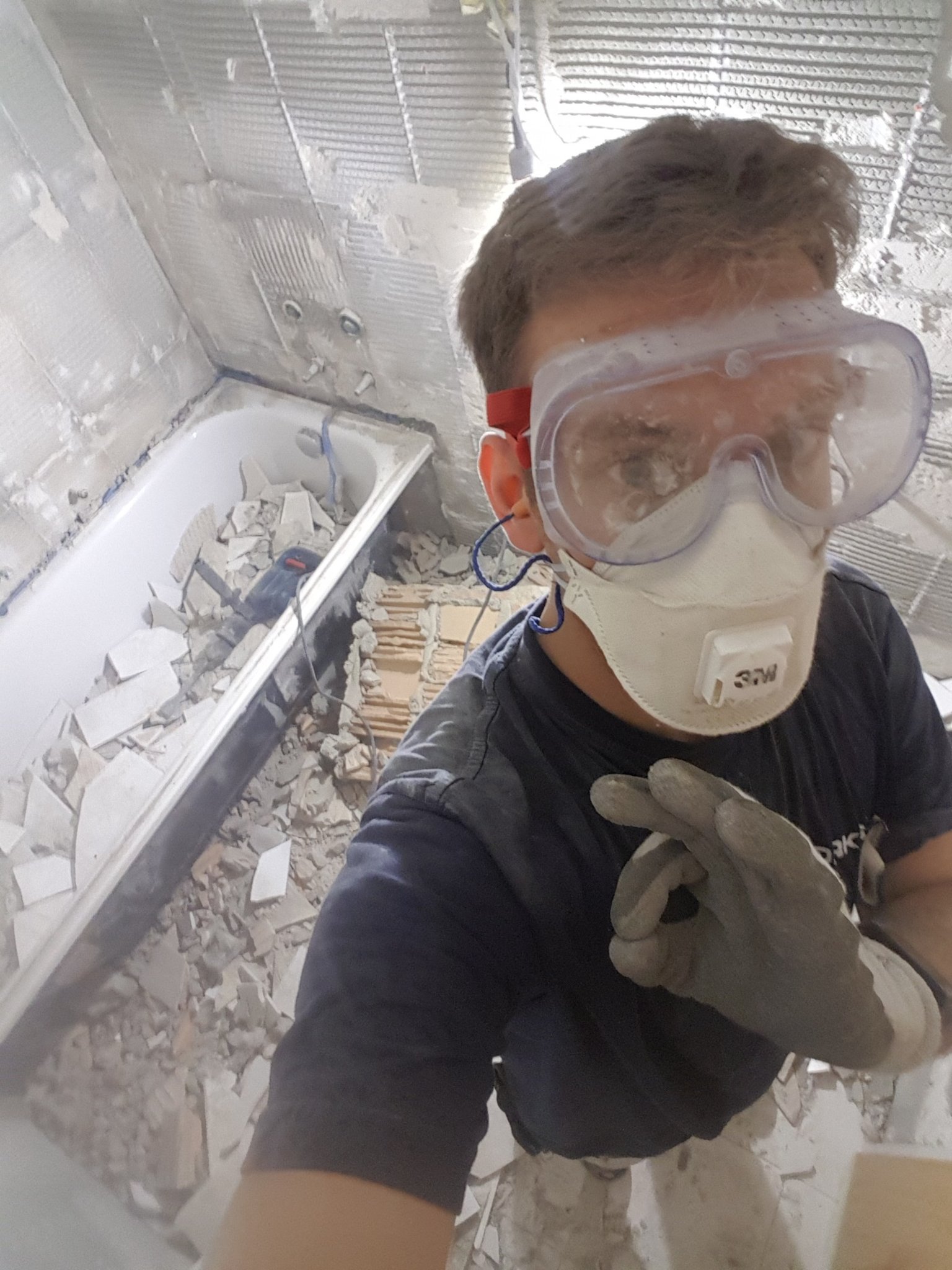 Plattenleger mit Schutzbrille und Maske beim Rückbau eines Bades