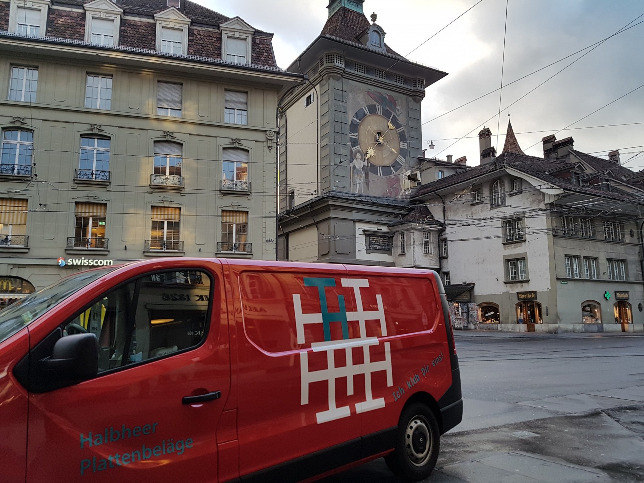 Roter Firmenbus mit Halbheer-Logo vor dem Zytglogge in Bern
